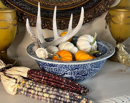 Blue and white phoenix porcelain bowl styled with pumpkins and antler décor on a console.