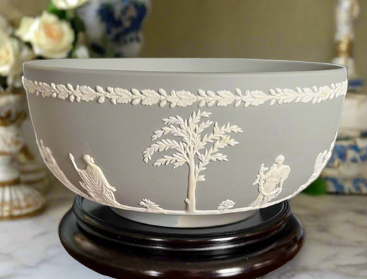 Gray Wedgwood Jasperware bowl with white neoclassical bas-relief figures and foliage, displayed on a wood stand.