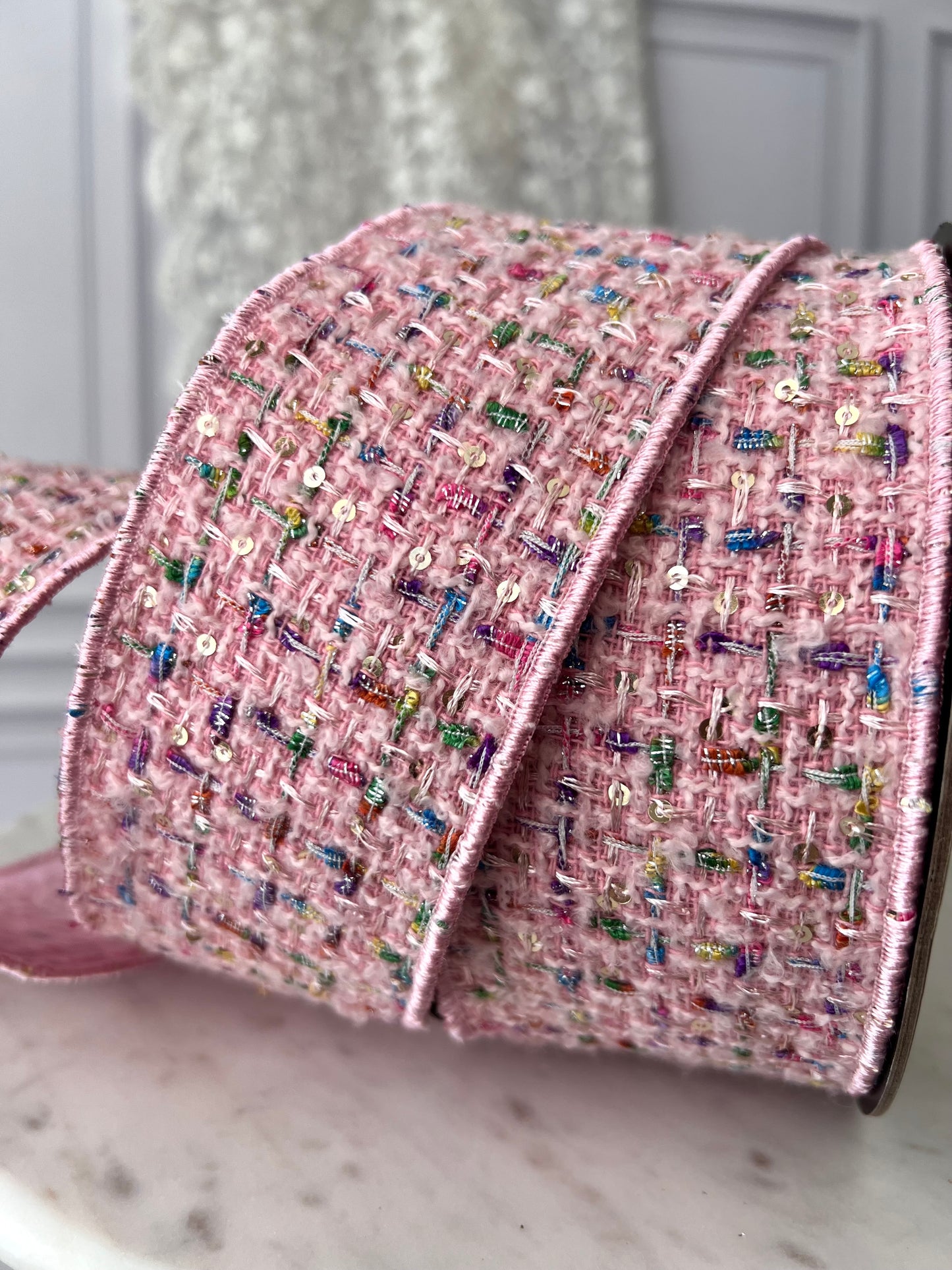 A textured blush bouclé ribbon with fine metallic threads and subtle sequins. Wired for shaping elegant bows and thoughtful finishing details.