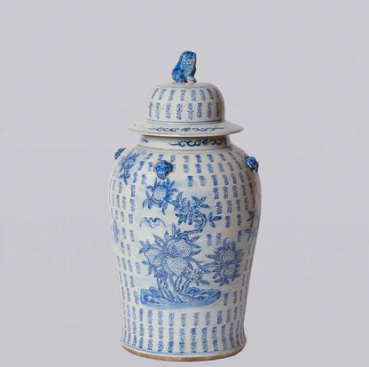 Large blue and white porcelain longevity temple jar featuring peaches, flowering branches, traditional motifs, and a foo lion finial lid.