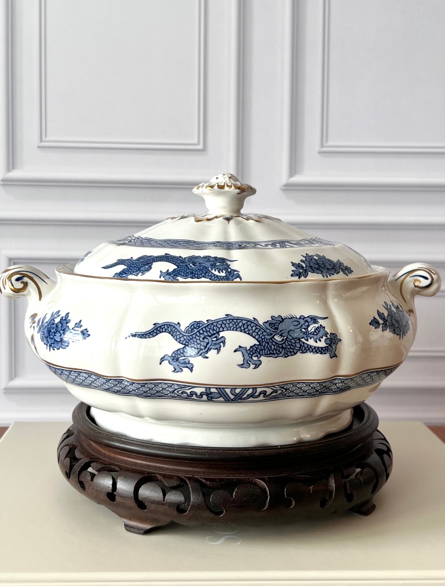 Vintage Booths Dragon covered tureen in blue and white English transferware displayed on a decorative stand. 