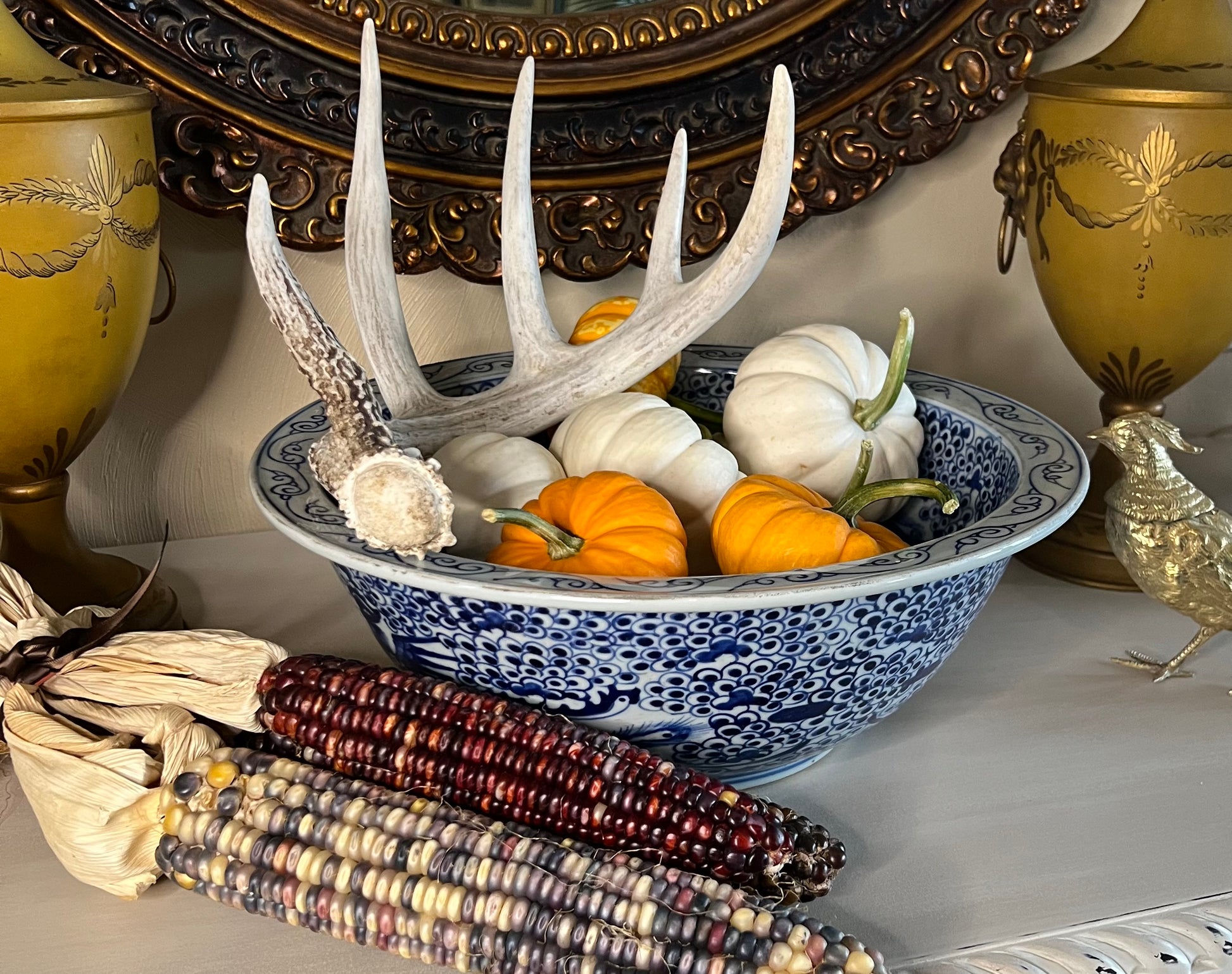 Blue and white phoenix porcelain bowl styled with pumpkins and antler décor on a console.