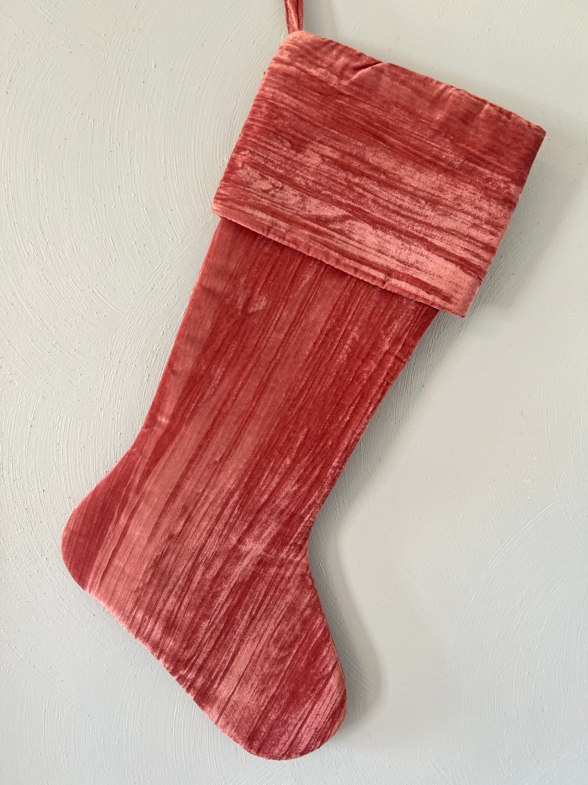 Coral crushed velvet Christmas stocking with wide folded cuff and hanging loop.
