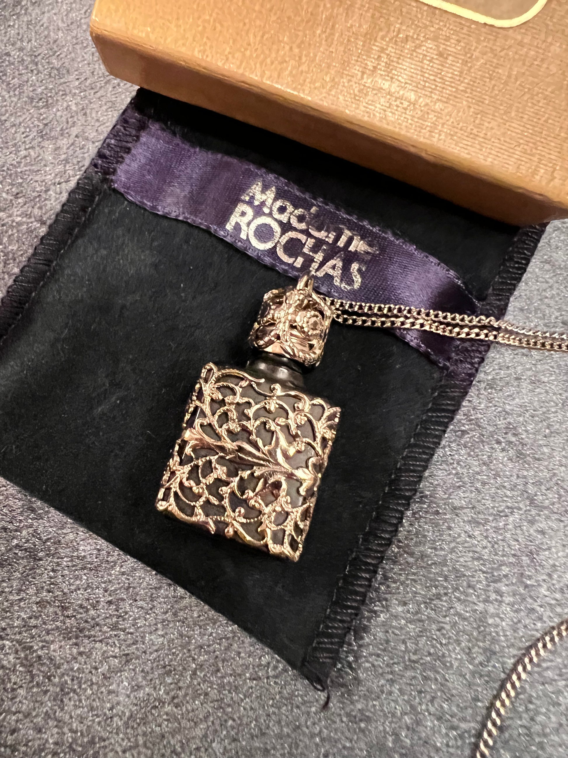 Vintage Rochas Paris perfume flacon necklace with ornate silver-tone filigree case and original pouch.