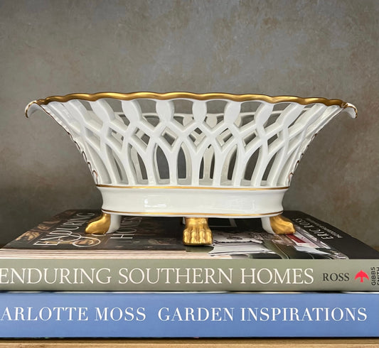 White and gold Vista Alegre reticulated porcelain bowl with scalloped rim and lion-paw feet displayed on books.